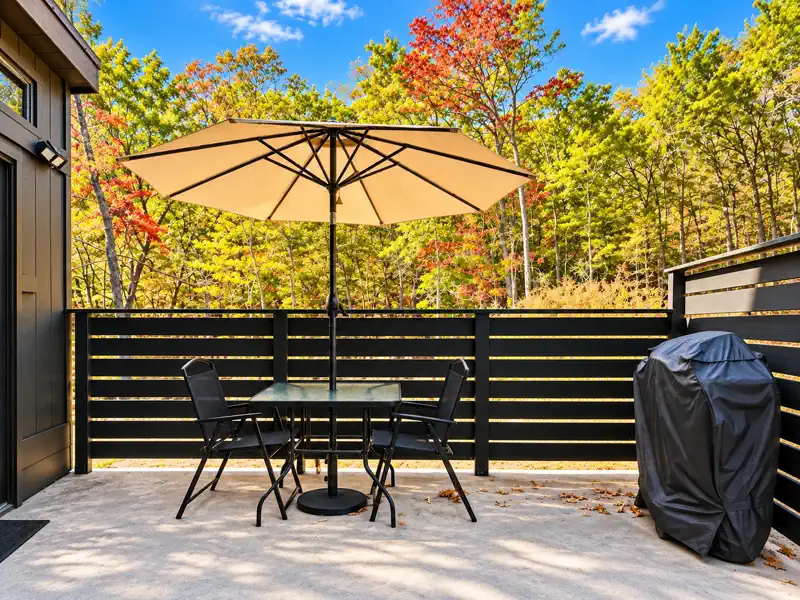 Private patio with outdoor dining and wooded views at Tiny on the Ridge