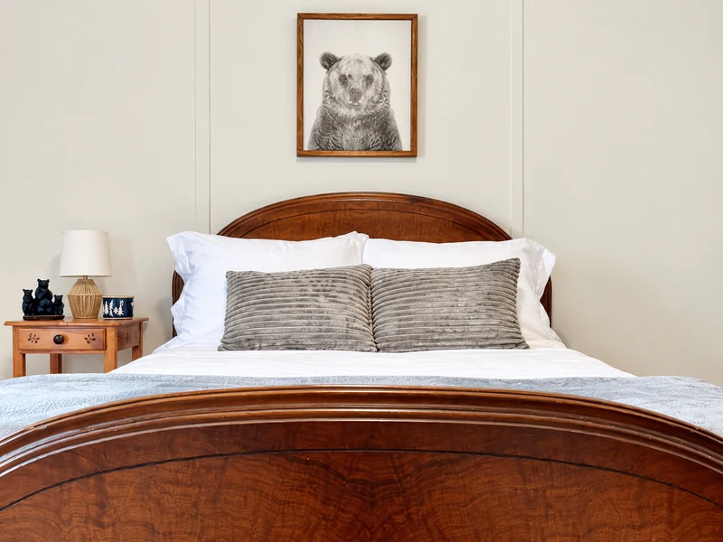 Full-size bed with white bedding and bear artwork in Casita’s second bedroom in Blue Ridge, Georgia.